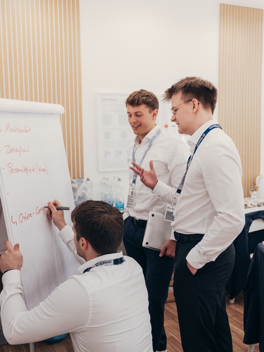 Drei Personen erarbeiten gemeinsam eine Liste am Flipchart