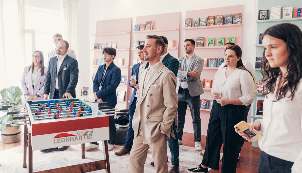 Gruppe an einem Kickertisch in einer JCNetwork-Lounge, im Hintergrund ein Bücherregal